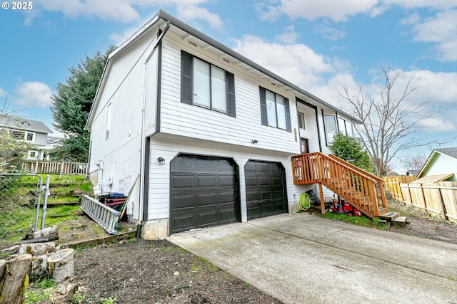 view of front of property with concrete driveway, an attached garage, and fence