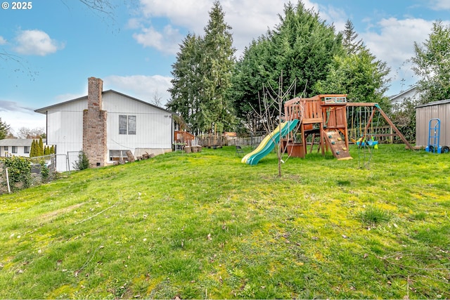 view of yard featuring an outbuilding, a playground, a storage unit, and fence