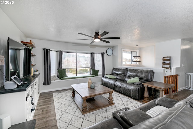 living area with light wood-style flooring, baseboards, and a textured ceiling