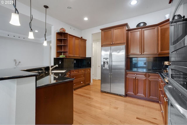 kitchen with decorative light fixtures, sink, stainless steel fridge, decorative backsplash, and light hardwood / wood-style floors