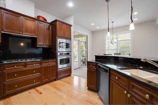 kitchen with sink, hanging light fixtures, stainless steel appliances, tasteful backsplash, and dark stone counters