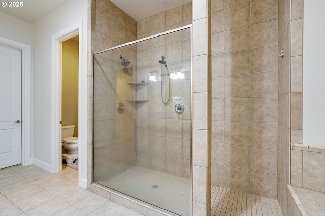 bathroom with tile patterned flooring, toilet, and a tile shower