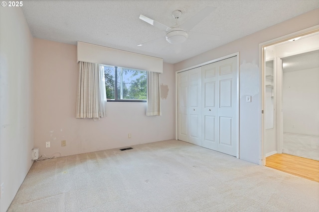 unfurnished bedroom featuring carpet flooring, a closet, a textured ceiling, and a ceiling fan