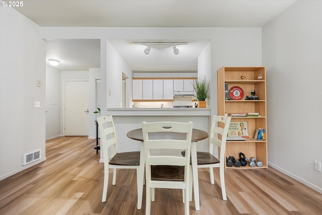 dining area with light wood-type flooring and baseboards