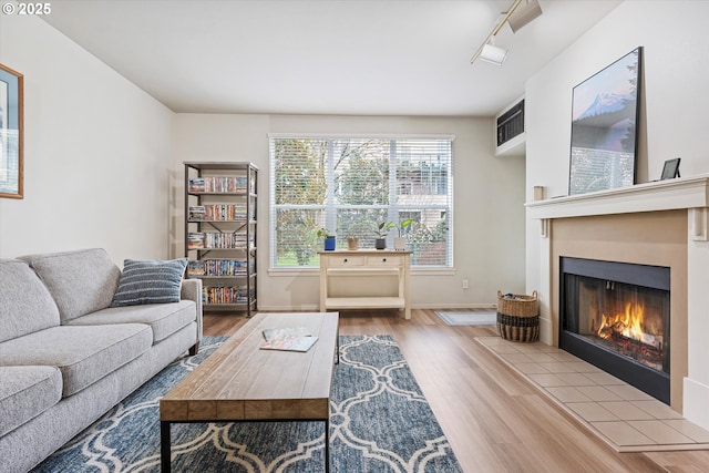 living room with wood finished floors, a warm lit fireplace, and track lighting