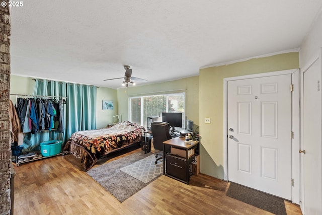 bedroom with a ceiling fan, wood finished floors, a closet, and a textured ceiling