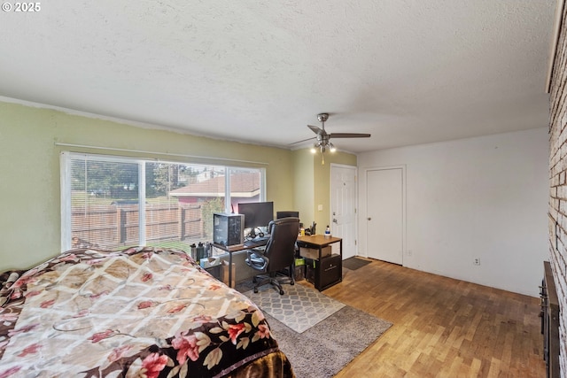 bedroom with a textured ceiling, wood finished floors, and a ceiling fan