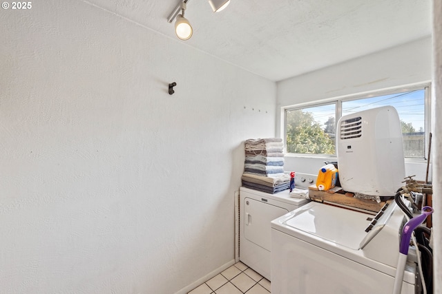 clothes washing area featuring baseboards, washer and clothes dryer, light tile patterned floors, laundry area, and a textured ceiling