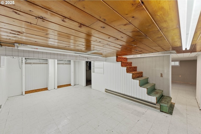 basement featuring tile patterned floors, a baseboard heating unit, wood ceiling, and stairway