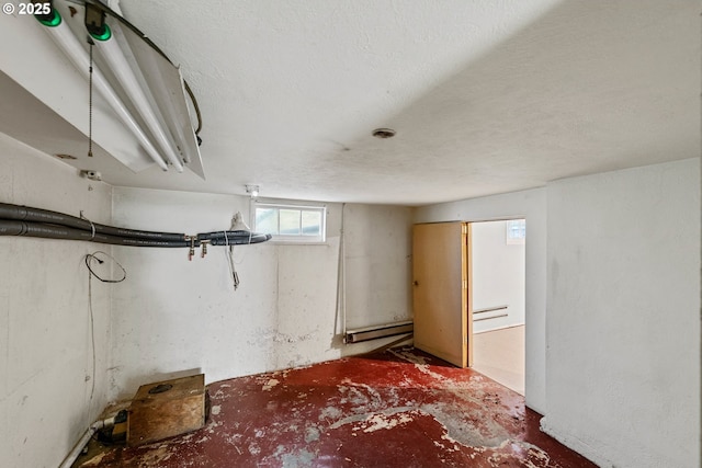 basement featuring baseboard heating and a textured ceiling