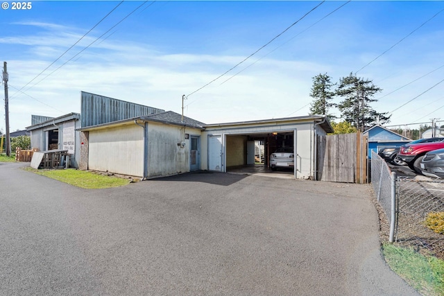 view of front of home with a garage, aphalt driveway, and fence