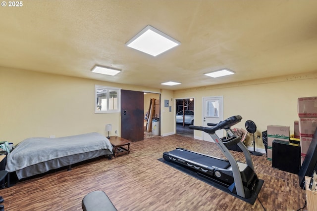 workout room with baseboards, a textured ceiling, and wood finished floors