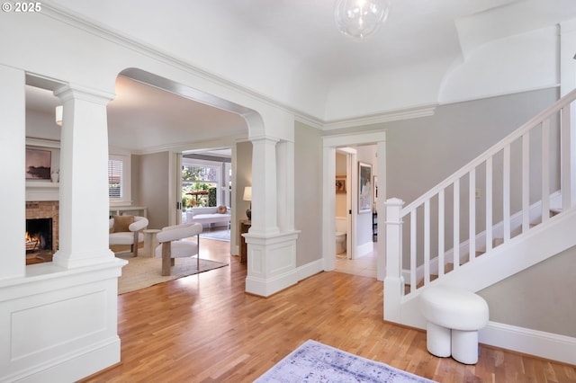 2215 NE 24th Ave, Portland, OR 97212 - entrance foyer with decorative columns, light wood-type flooring, stairway, a fireplace, and crown molding