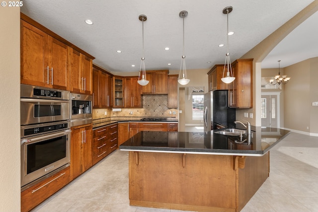 205 W Oriole Dr, Roseburg, OR 97471 - kitchen featuring a peninsula, backsplash, light tile patterned flooring, brown cabinets, and stainless steel appliances