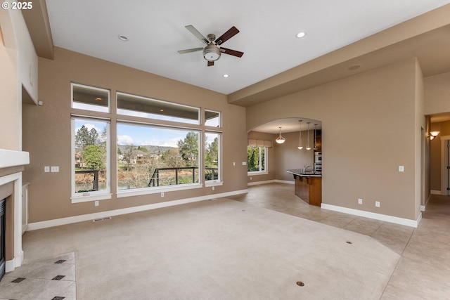 205 W Oriole Dr, Roseburg, OR 97471 - unfurnished living room featuring baseboards, a ceiling fan, a fireplace with flush hearth, visible vents, and arched walkways