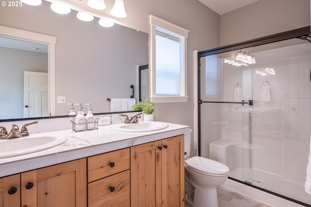 bathroom featuring a sink, a shower stall, toilet, and double vanity