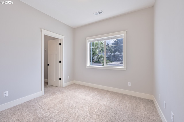 spare room featuring visible vents, baseboards, and light colored carpet