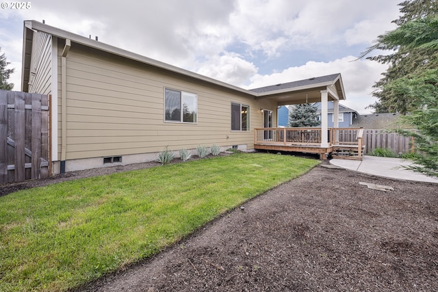 rear view of property with fence, a patio, a yard, and a deck