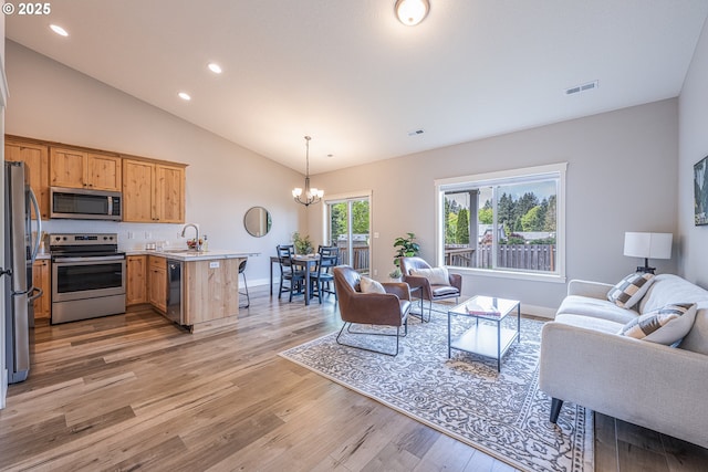 living area with visible vents, a notable chandelier, light wood-style floors, lofted ceiling, and recessed lighting