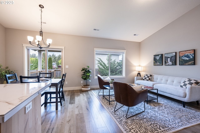 living room with visible vents, a chandelier, a wealth of natural light, and light wood finished floors