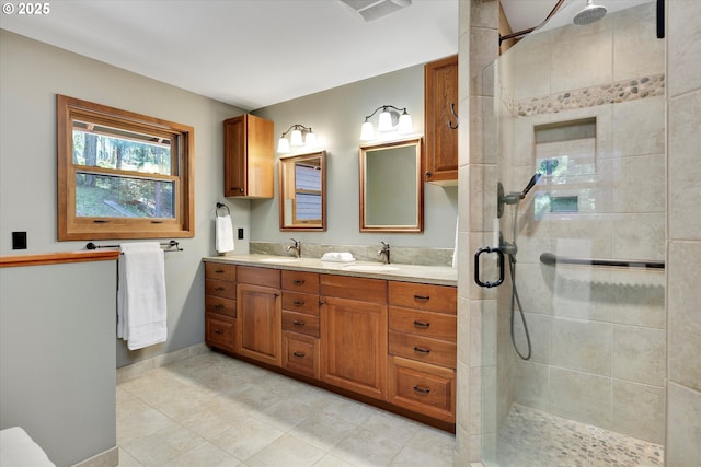 full bathroom featuring a tile shower, tile patterned floors, double vanity, and baseboards