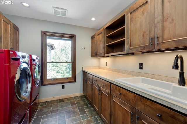 clothes washing area featuring cabinet space, baseboards, washing machine and dryer, recessed lighting, and stone finish floors