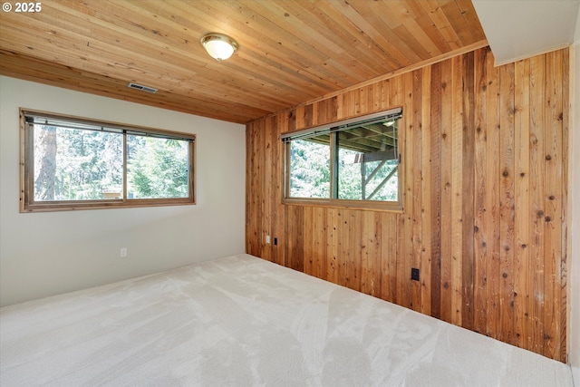 unfurnished room with plenty of natural light, wood walls, wooden ceiling, and carpet floors