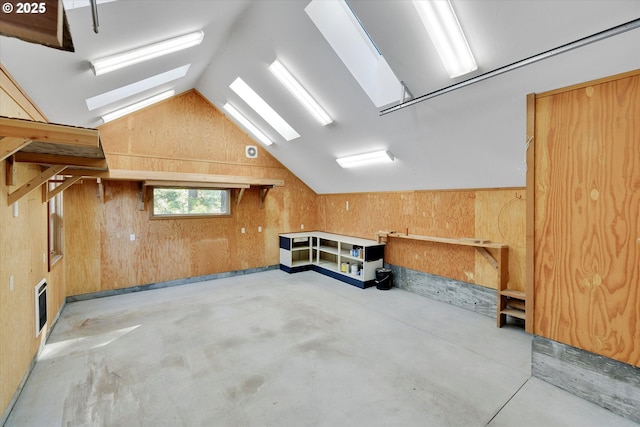 additional living space with a skylight, lofted ceiling, concrete floors, and wooden walls