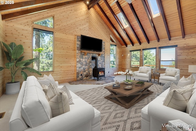 living room with wood walls, a wood stove, beamed ceiling, and wood ceiling