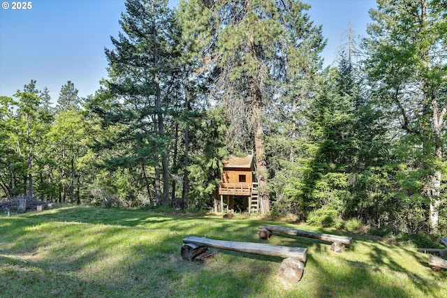 view of grassy yard with stairs, a forest view, and a deck