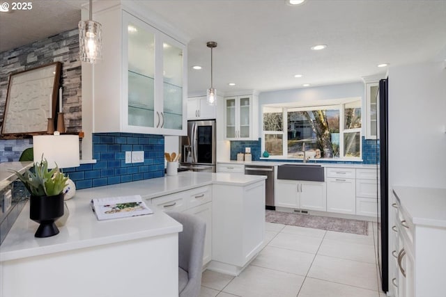 kitchen featuring hanging light fixtures, appliances with stainless steel finishes, a sink, and white cabinets