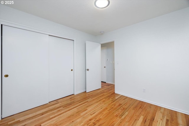 unfurnished bedroom with light wood-style flooring and a closet