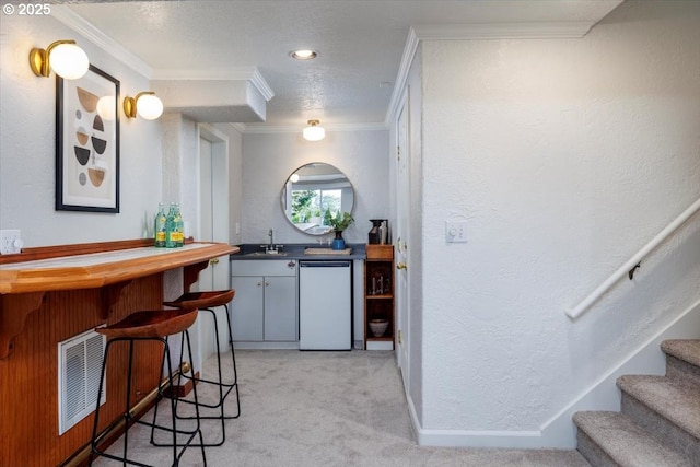 bar with indoor wet bar, visible vents, light carpet, a sink, and stairs