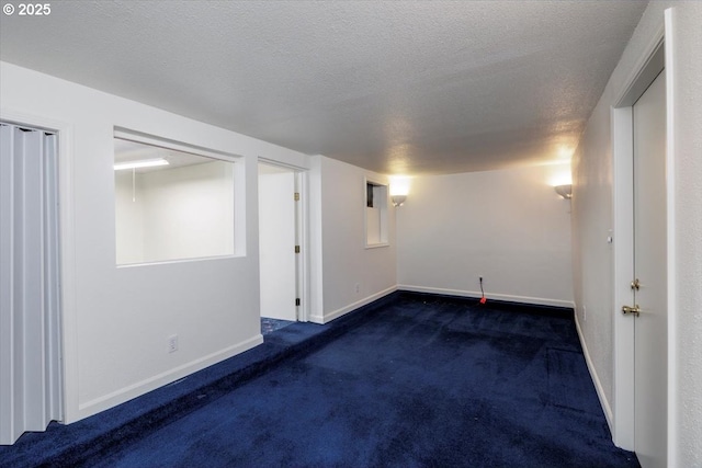 finished below grade area with carpet, a textured ceiling, and baseboards