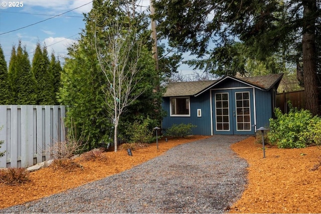 ranch-style house featuring french doors, gravel driveway, and fence