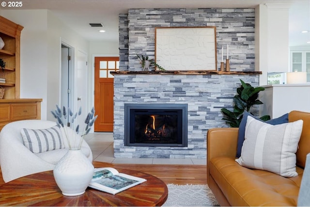 living room with recessed lighting, visible vents, a fireplace, and wood finished floors