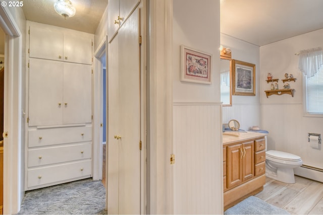 385 S Green St, Heppner, OR 97836 - bathroom with vanity, a wainscoted wall, a baseboard radiator, and wood finished floors