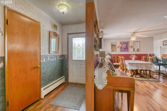 385 S Green St, Heppner, OR 97836 - entrance foyer with a baseboard heating unit, wood finished floors, a ceiling fan, and wallpapered walls