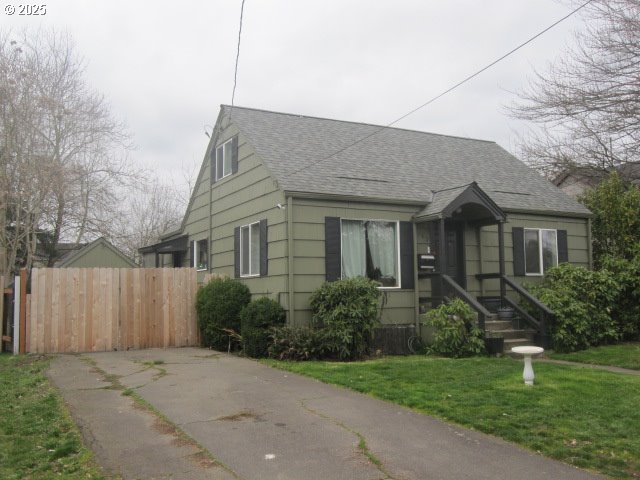 bungalow featuring fence, a front lawn, and roof with shingles