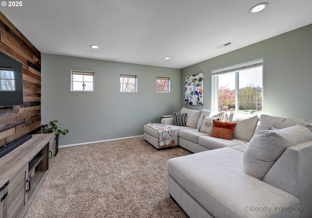 living area with wooden walls, visible vents, recessed lighting, and carpet