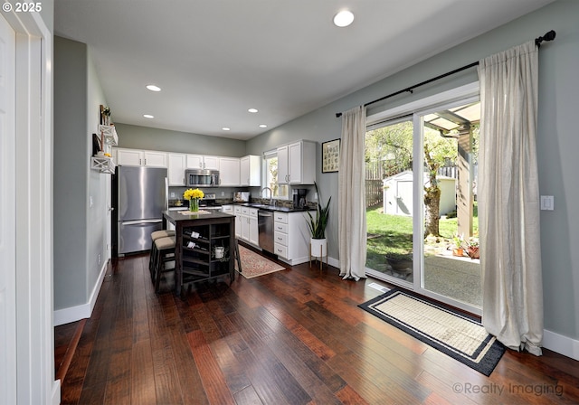 kitchen featuring stainless steel appliances, a healthy amount of sunlight, a sink, and dark countertops