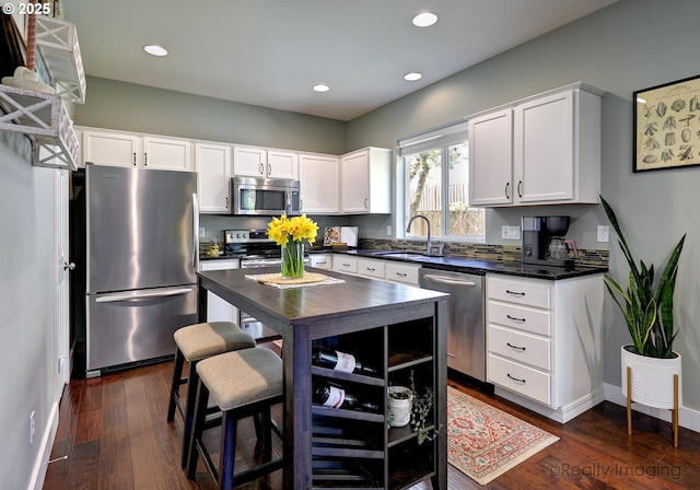 kitchen featuring dark wood-style flooring, white cabinetry, dark countertops, appliances with stainless steel finishes, and a sink