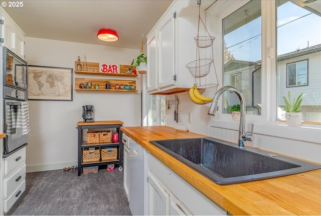 kitchen featuring black oven, butcher block countertops, white cabinetry, sink, and dark wood-type flooring