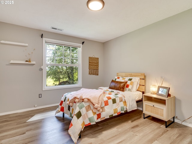 bedroom featuring visible vents, baseboards, and wood finished floors