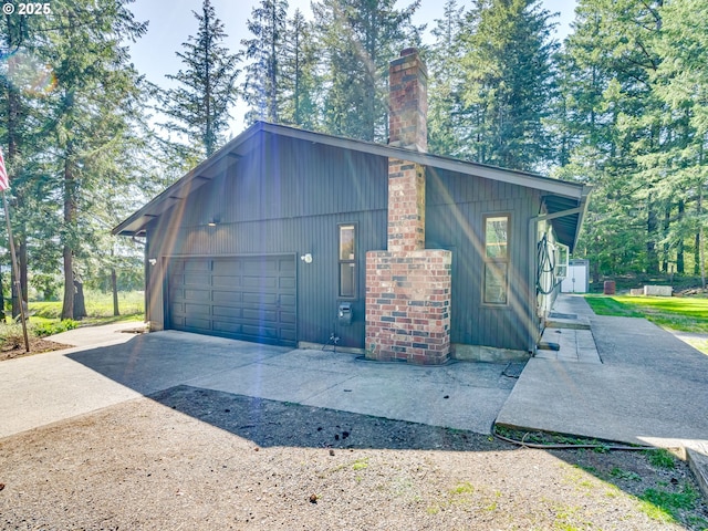 view of property exterior with a garage, driveway, and a chimney