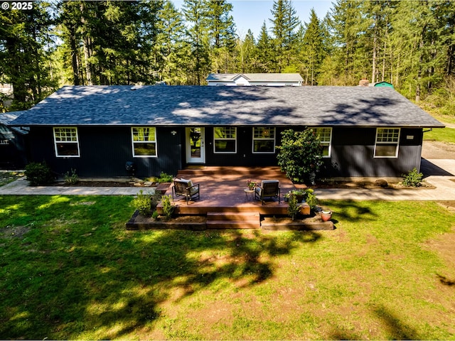 single story home featuring a front lawn, a shingled roof, and a wooden deck