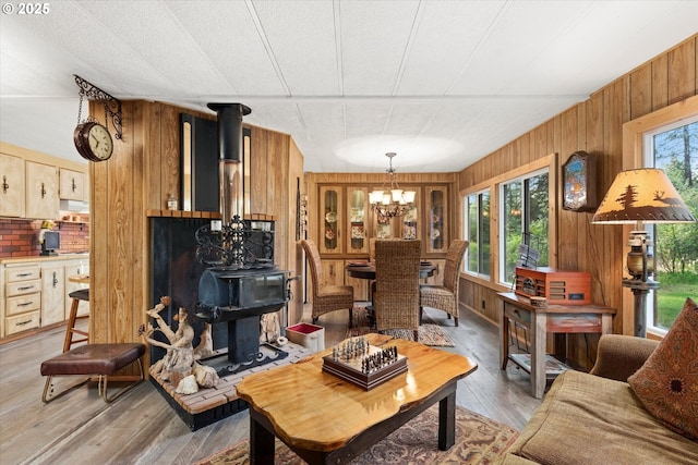 74576 Thompson Rd, Elgin, OR 97827 - living room with a wood stove, wood walls, a chandelier, and light wood-style flooring
