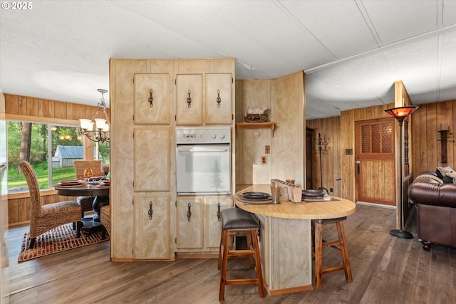 74576 Thompson Rd, Elgin, OR 97827 - kitchen with oven, wood walls, dark wood finished floors, a chandelier, and light brown cabinetry
