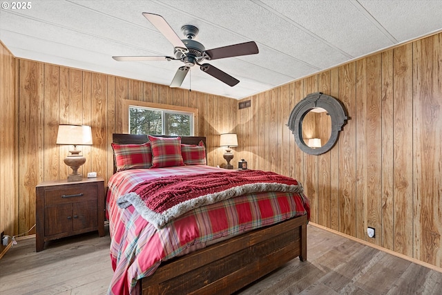74576 Thompson Rd, Elgin, OR 97827 - bedroom featuring wooden walls, wood finished floors, a textured ceiling, and a ceiling fan