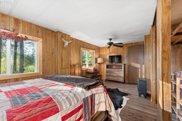 74576 Thompson Rd, Elgin, OR 97827 - bedroom featuring wooden walls, wood finished floors, a wood stove, and a ceiling fan